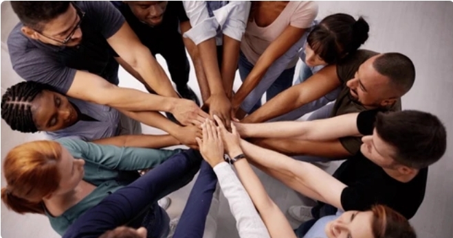 L’image montre un groupe de personnes unissant leurs mains au centre, symbolisant l’unité et la coopération.