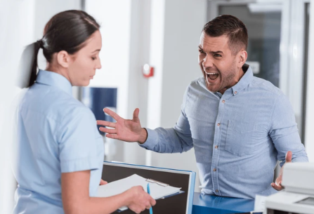 Image illustrant une situation de conflit ou de désaccord en milieu professionnel, avec un homme furieux gesticulant face à une employée calme en uniforme. Cette scène représente des thèmes tels que la gestion des conflits, la communication difficile, ou le stress en milieu de travail. Parfaite pour des articles ou des contenus liés à la gestion de la relation client, la formation en communication, ou les environnements de travail tendus.