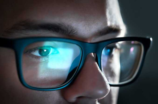 un gros plan flou sur le visage d’une personne, se concentrant sur la région de l’œil. L’œil est partiellement obscurci par ce qui semble être la monture d’une paire de lunettes avec une réflexion sur la lentille. Cette image est idéale pour illustrer des sujets liés à la vision, aux lunettes, à la réflexion et aux détails visuels.